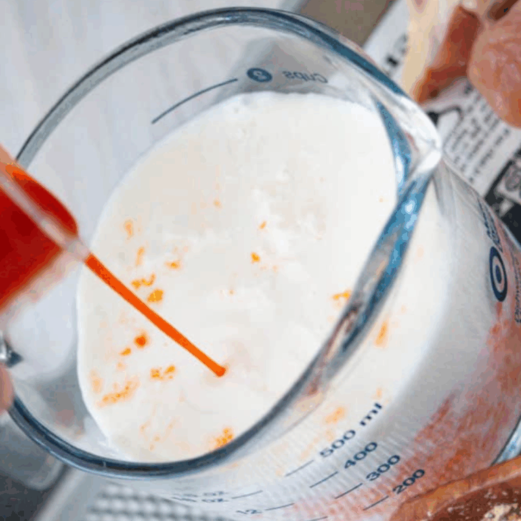 Chicken being seasoned with spices and soaked in buttermilk mixture