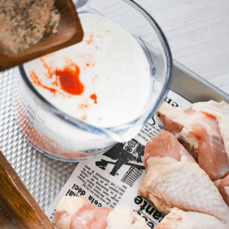 Chicken soaking in buttermilk and seasoning mixture inside a resealable bag