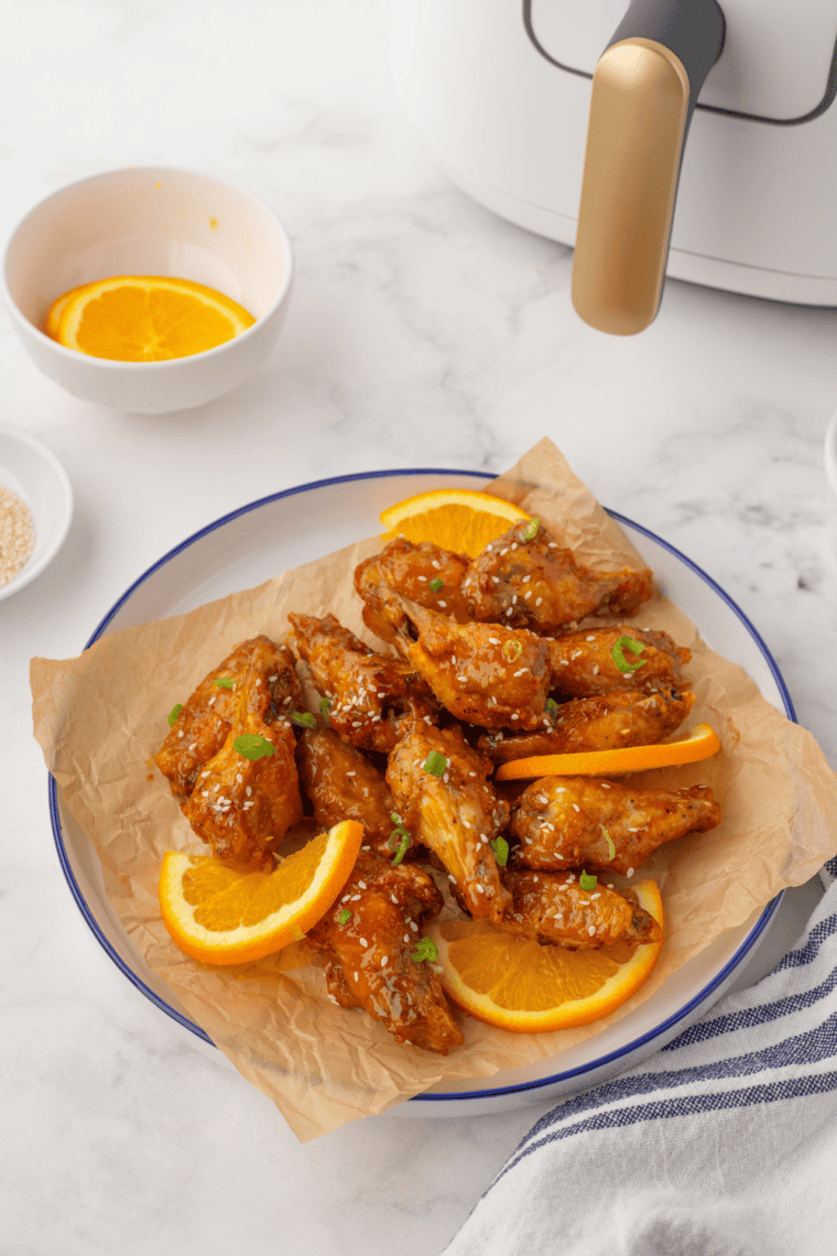 Crispy gluten-free chicken wings on a plate, garnished with herbs and served with dipping sauce.