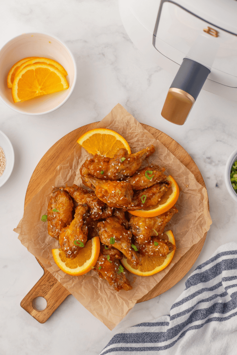 Golden, crispy gluten-free chicken wings on a plate, garnished with herbs and served with dipping sauce.