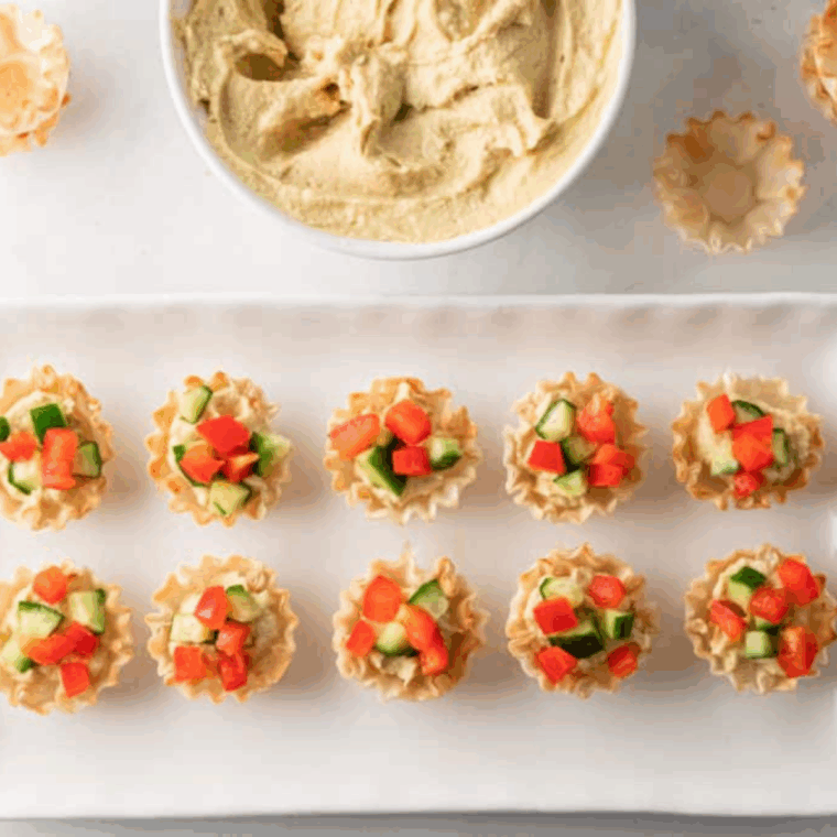 Greek hummus phyllo bites in crispy phyllo cups topped with cucumber, red pepper, and feta cheese