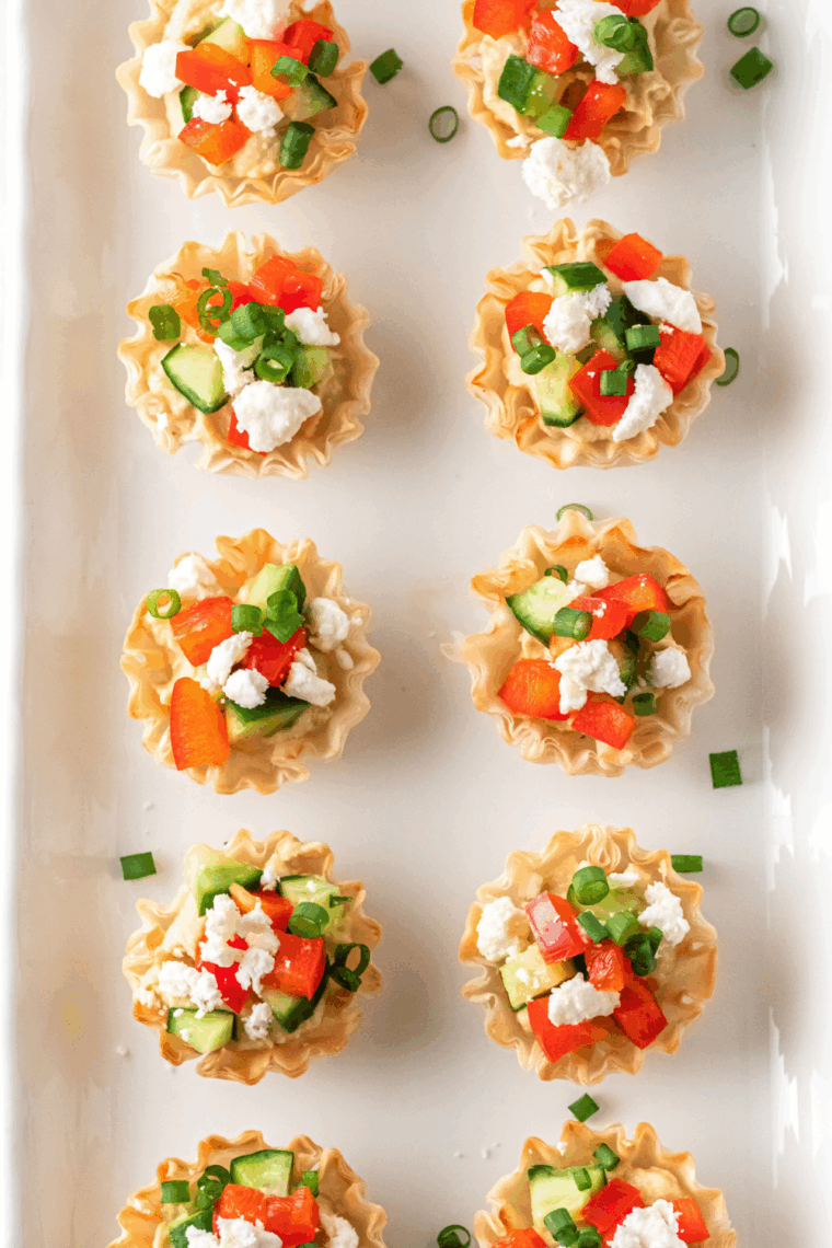 Greek hummus phyllo bites with crispy phyllo cups, hummus, cucumber, red pepper, and feta cheese on a platter