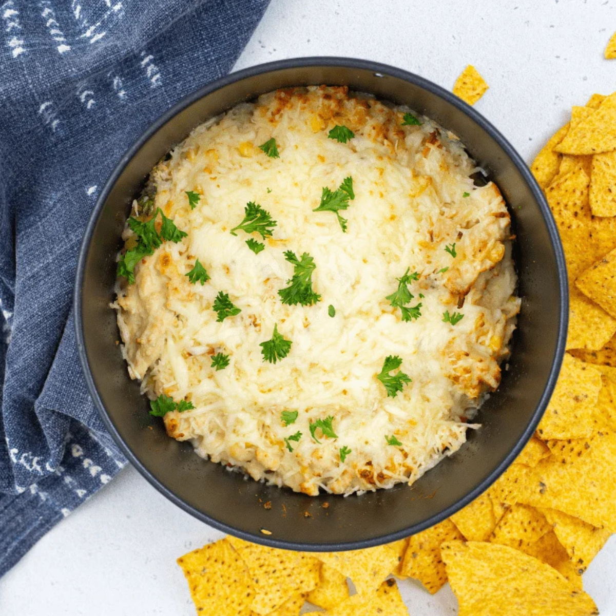 Cast iron skillet of white chicken chili dip cooking inside an air fryer basket