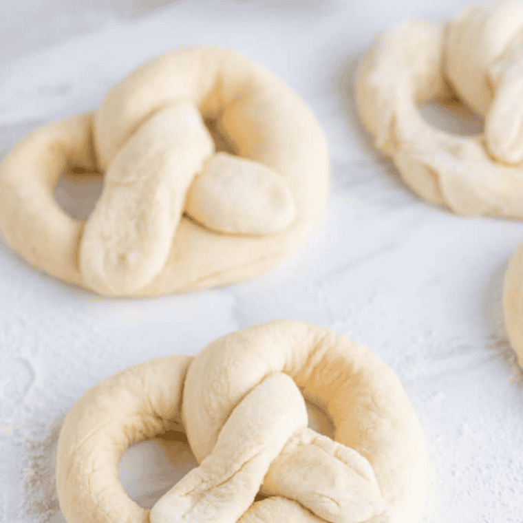 Dough rolled into a rope and twisted into a soft pretzel shape on a floured surface