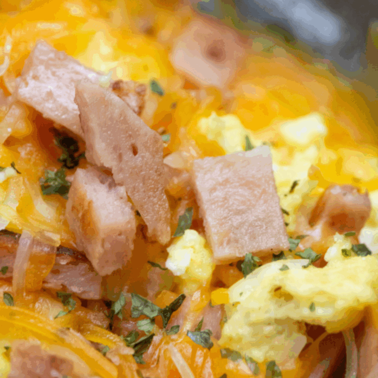 Air fryer basket with crispy Spam slices and eggs cooking together for an easy country-style breakfast.