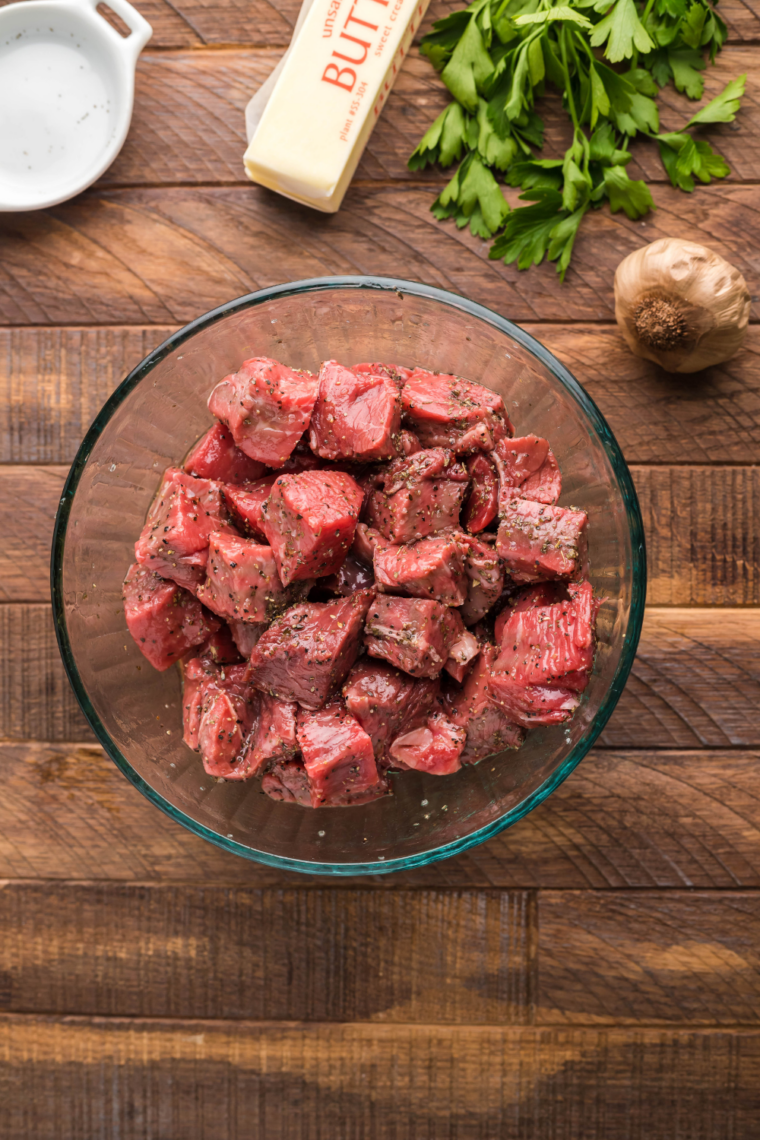 Raw steak cut into evenly sized cubes on a cutting board, trimmed and sliced against the grain for tenderness.