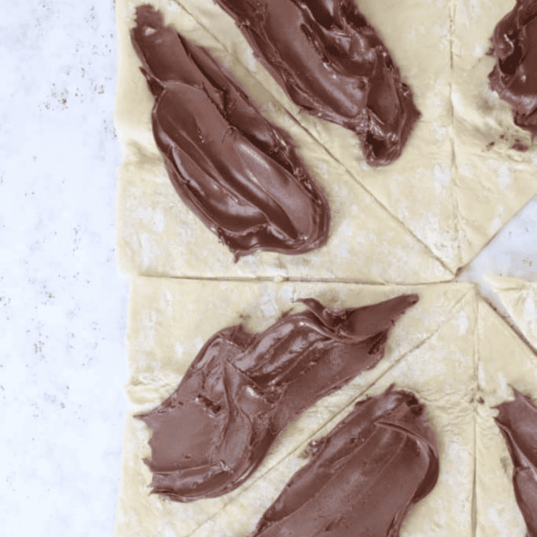 Rolling puff pastry dough and pinching edges to seal Nutella filling inside churros before air frying.