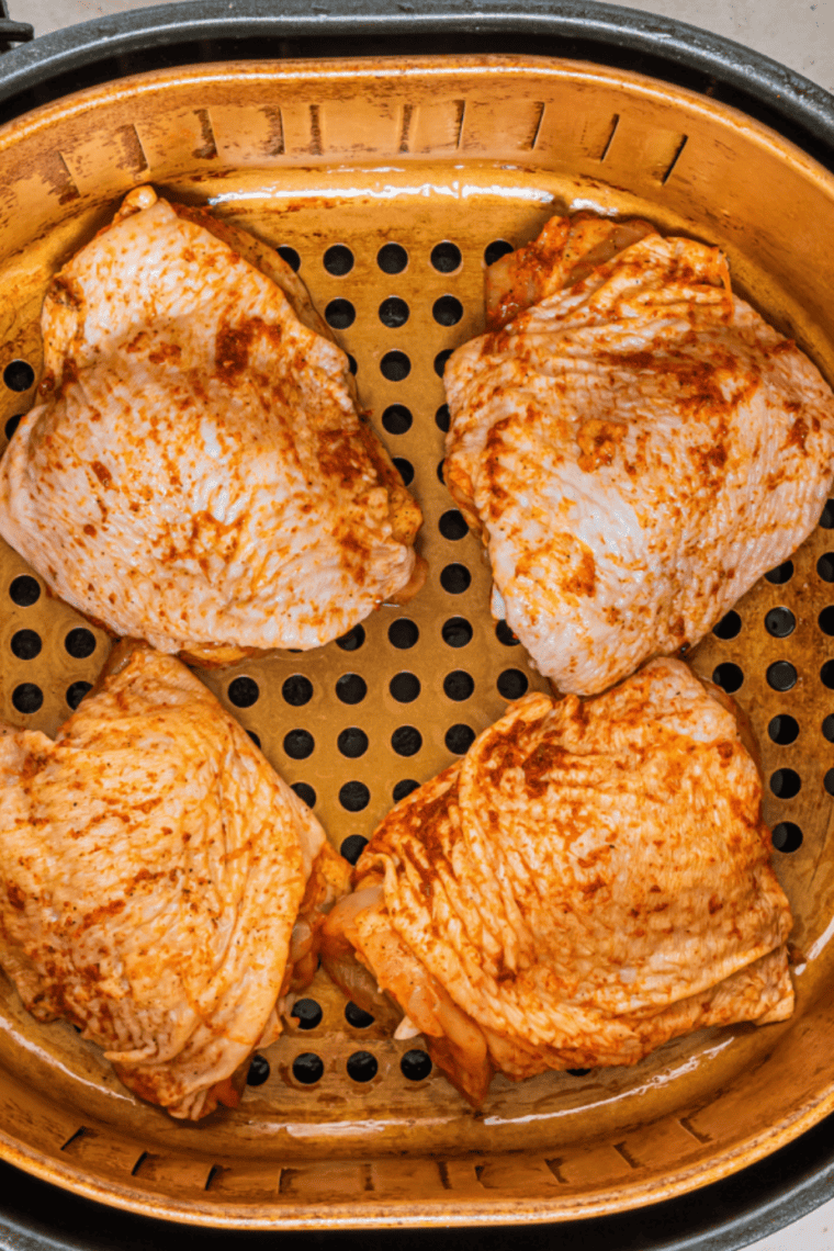 Raw chicken pieces being seasoned with salt and pepper, soaking in spicy peri peri marinade in a bowl.