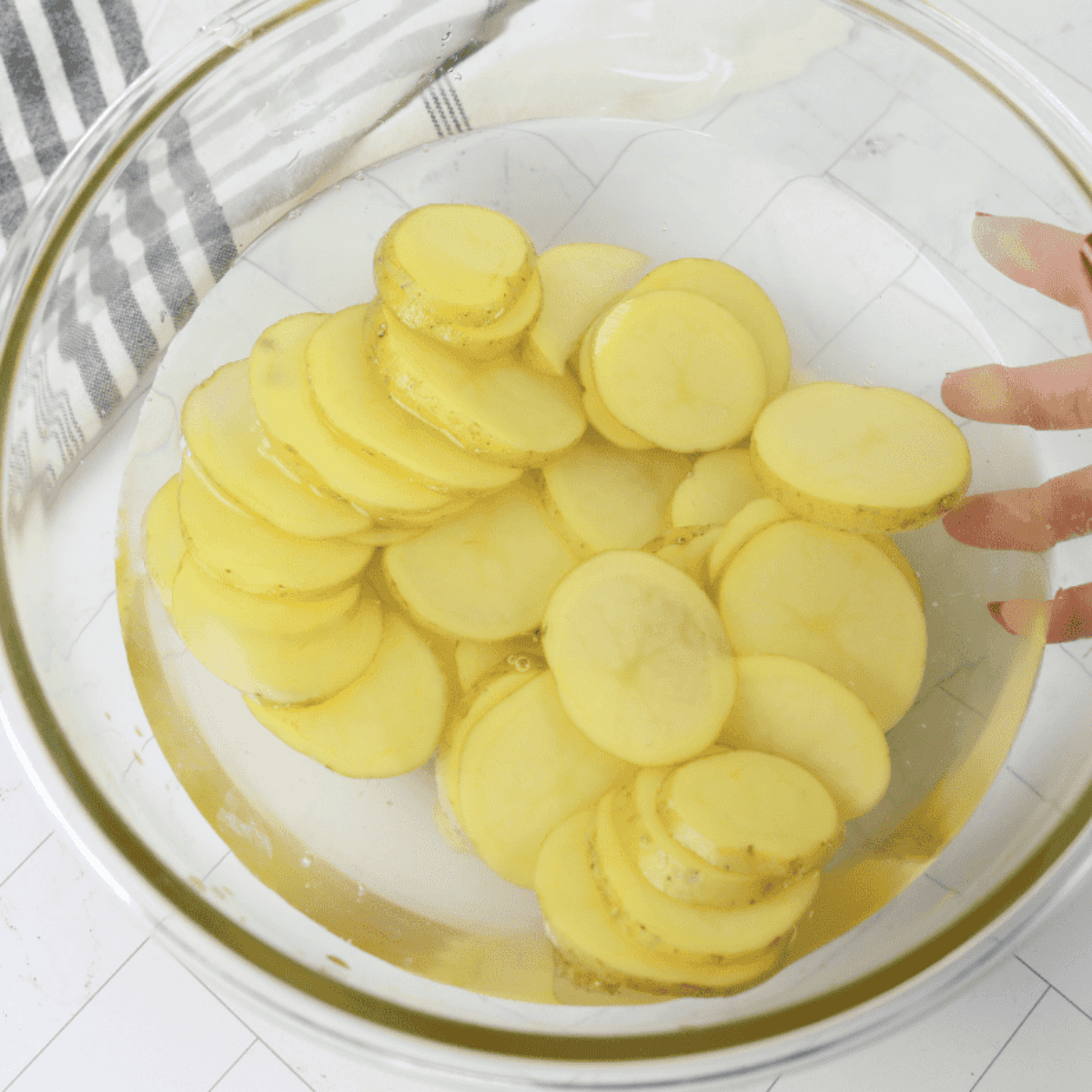 Sliced potatoes soaking in cold water in a bowl.