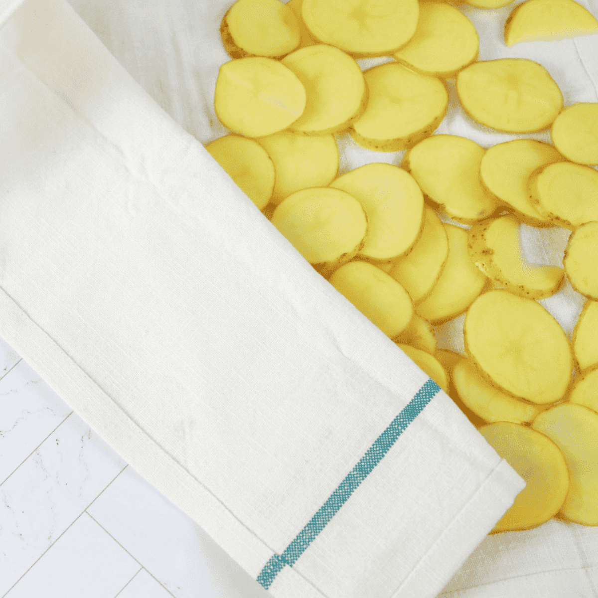 Draining and drying potato slices on a towel for crispiness.