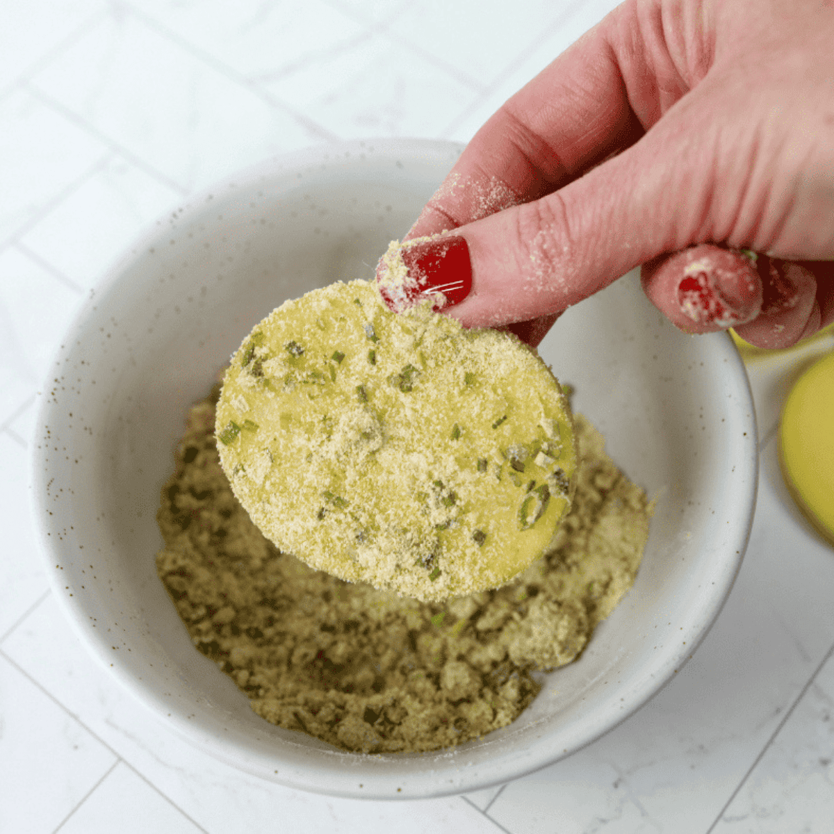 Seasoning mixture of buttermilk powder, onion powder, and chives with potato chips being coated.