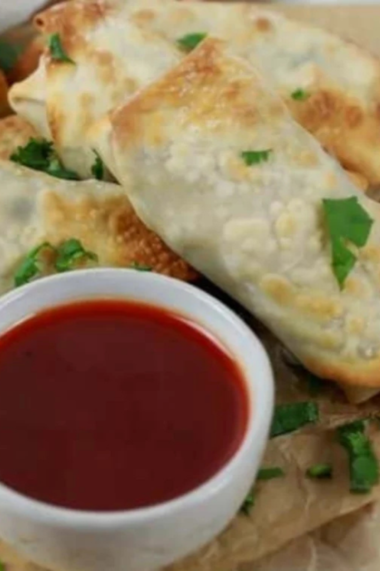 Plate of crispy air fryer chicken cilantro egg rolls served with sweet and sour dipping sauce