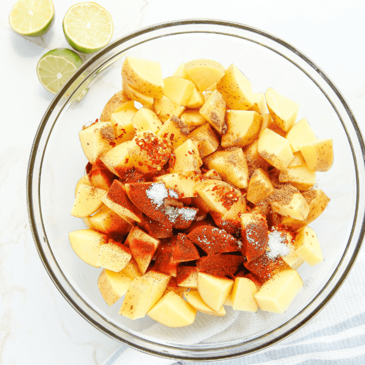 Diced potatoes in a large bowl, tossed with olive oil and seasonings, ready to cook.