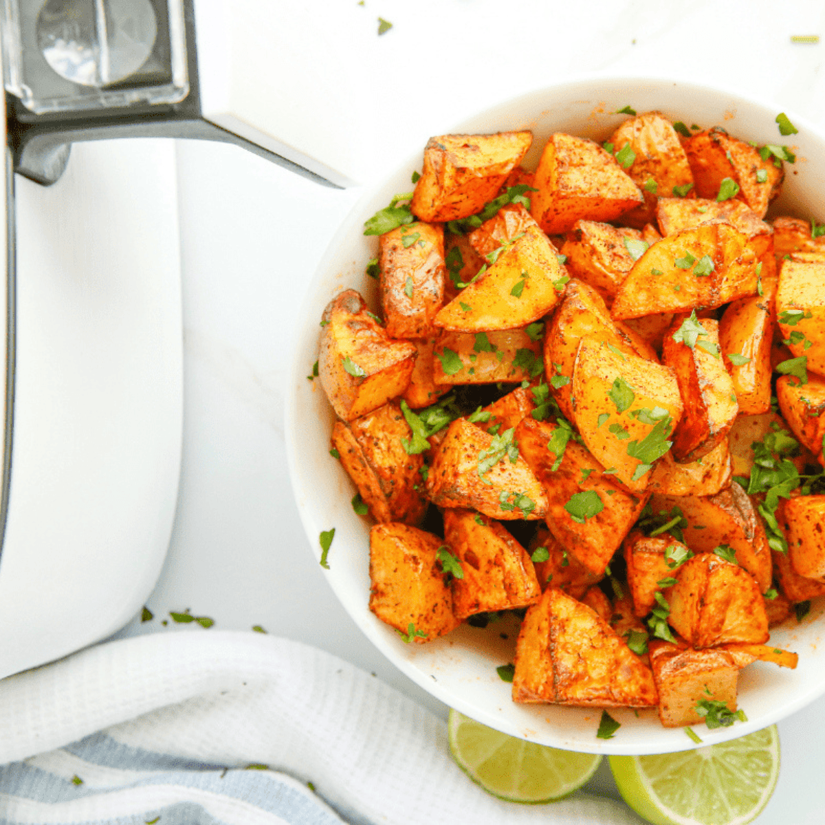 Golden air fryer chili lime potatoes, crispy on the outside, tender inside, garnished with lime and cilantro.