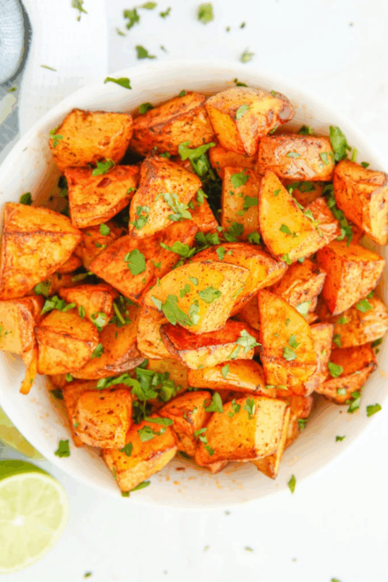 Golden, crispy air fryer chili lime potatoes, tender inside, garnished with lime and cilantro.