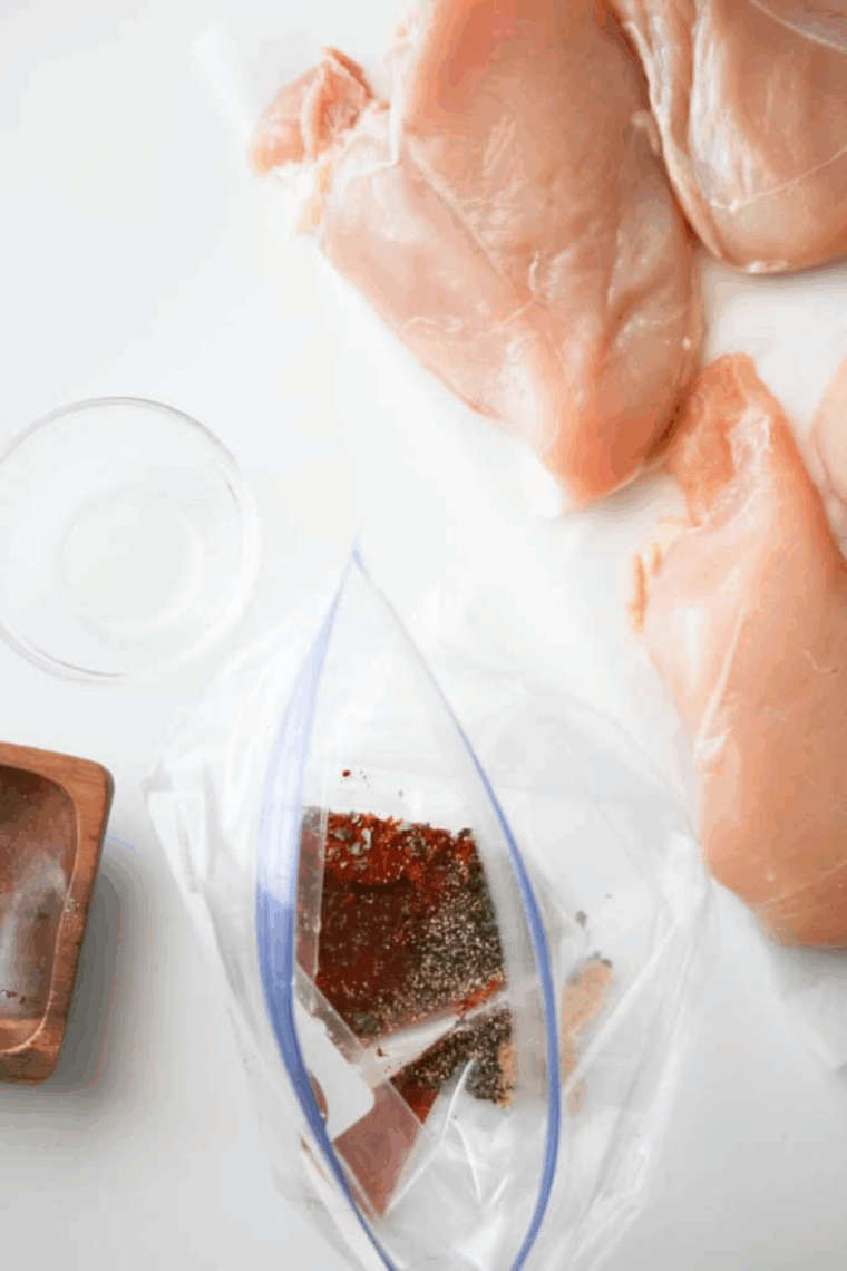 Chicken marinating in lemon juice with spices and olive oil