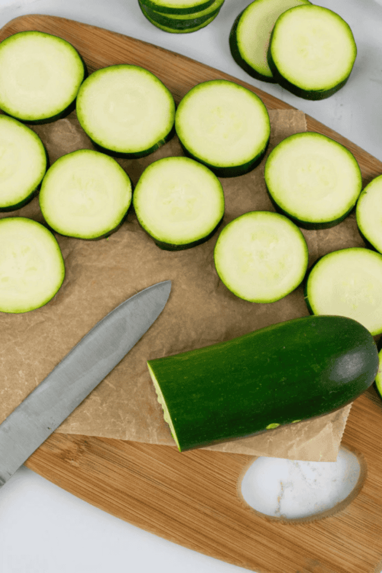 Thin, evenly sliced zucchini on a cutting board ready for air fryer dehydration.