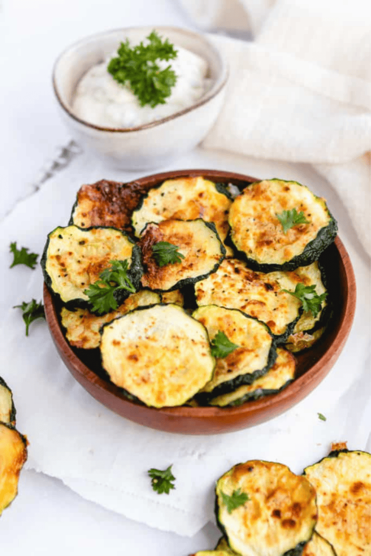 Zucchini slices arranged on a baking sheet inside an air fryer, cooking to crispy perfection.