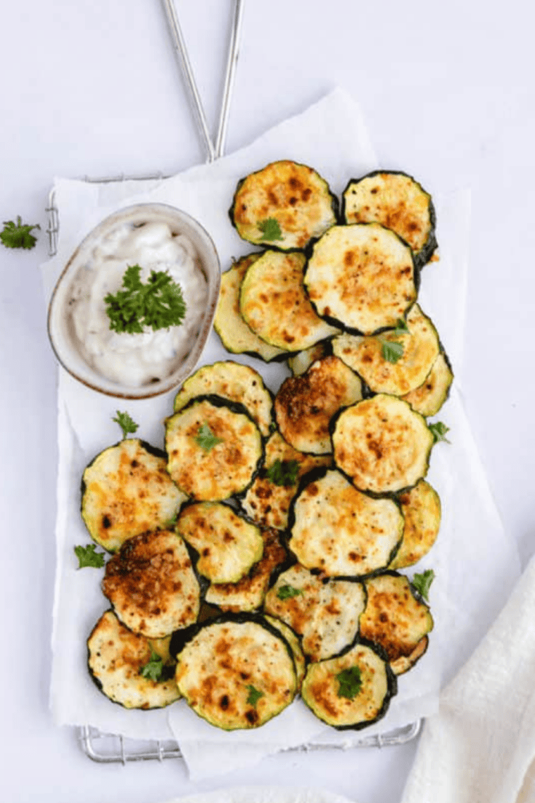 Crispy, golden dehydrated zucchini slices served on a plate, made in an air fryer.