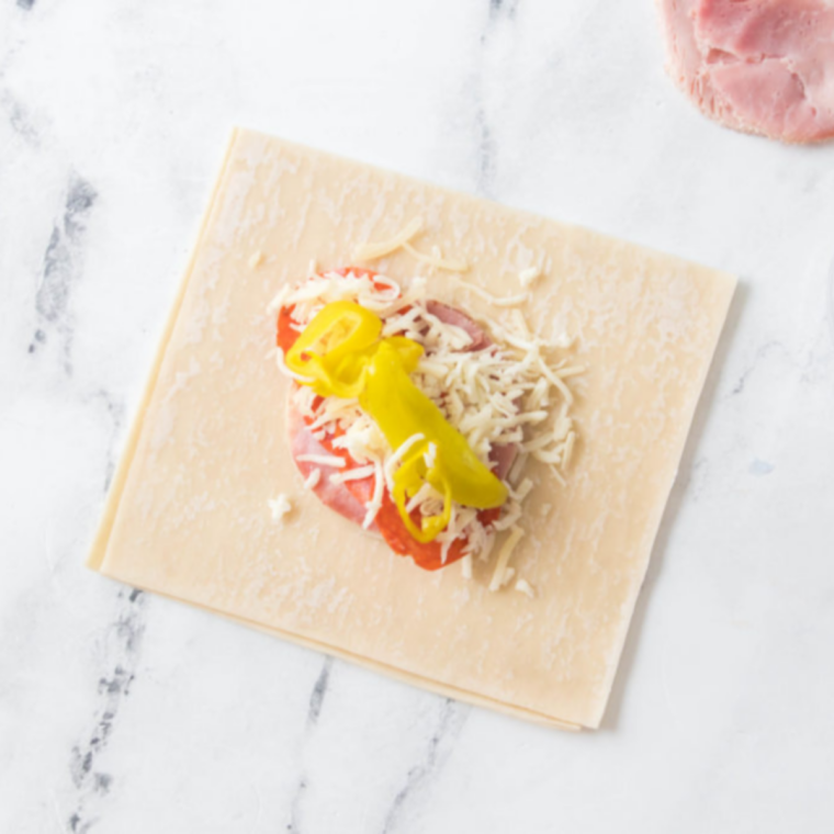 Provolone, ham, pepperoni, mozzarella and pepperoncini layered in a compact log on an egg roll wrapper