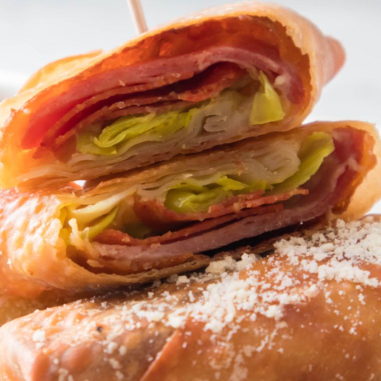 Close up of crispy air fryer antipasto egg rolls with melted provolone showing at the cut edge