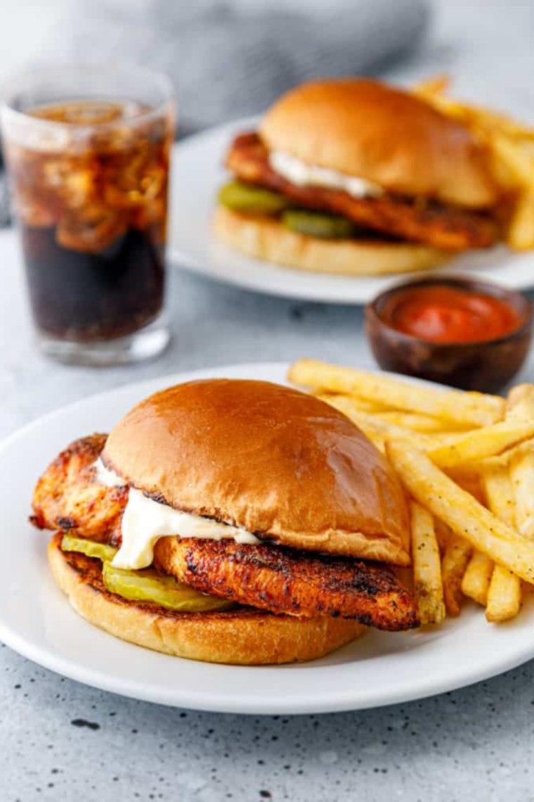 Blackened chicken sandwich on a toasted brioche bun with lettuce, tomato and pickles