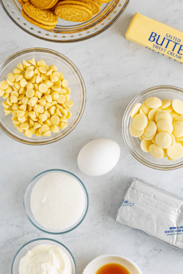 Ingredients for air fryer cheesecake bars: golden Oreos, cream cheese, sour cream, egg, sugar, butter, white chocolate chips