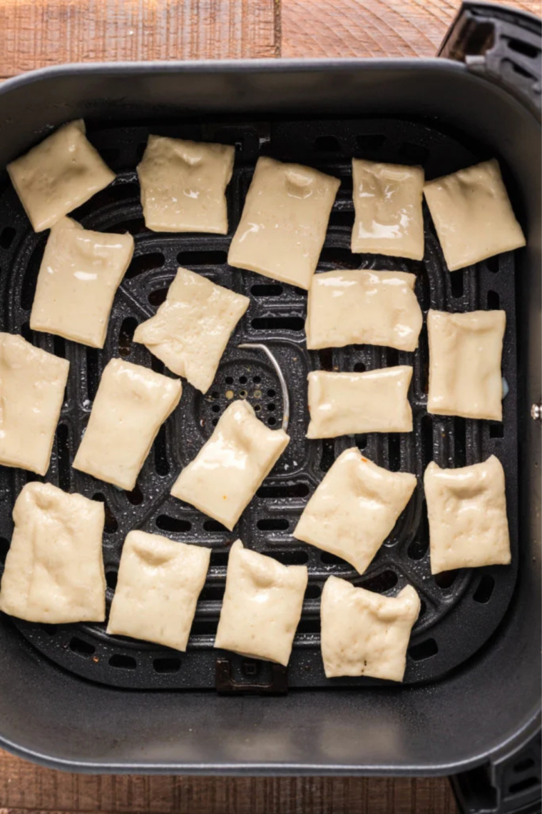 Buttered dough squares arranged in a single layer in an air fryer basket