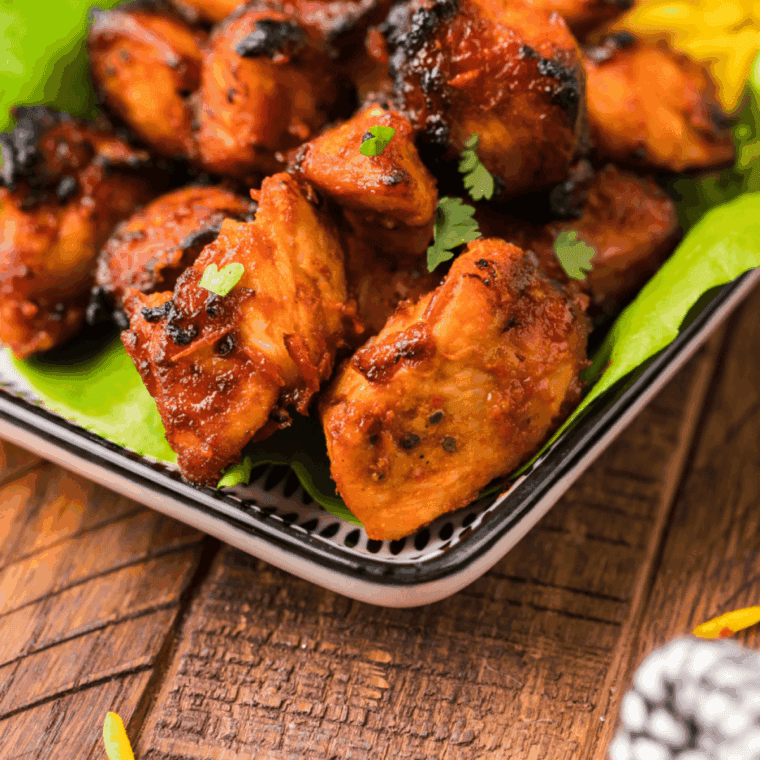 Golden-brown Air Fryer Guava Chicken glazed with sweet, tangy tropical sauce, served on a plate with fresh herbs.