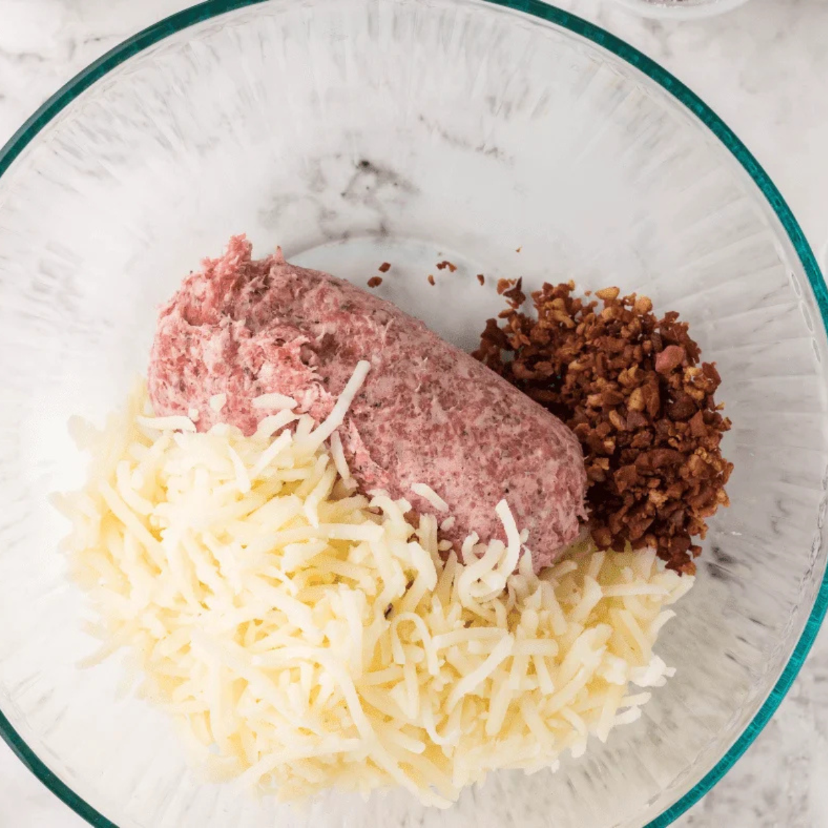 Air Fryer Sausage Balls mixture being combined in a large bowl with sausage, hash browns, cheddar, and cream cheese