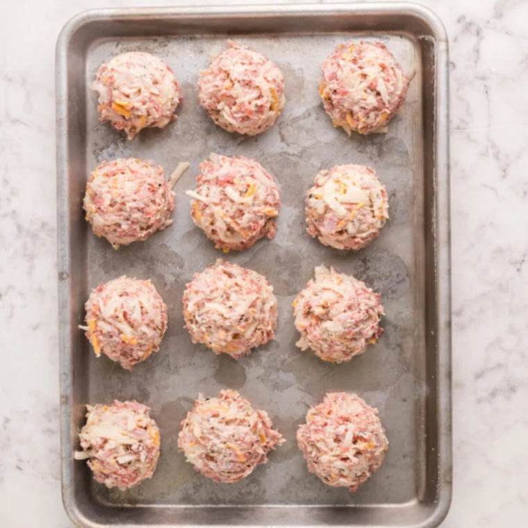 Uncooked Air Fryer Sausage Balls arranged on a baking sheet ready to chill in the freezer