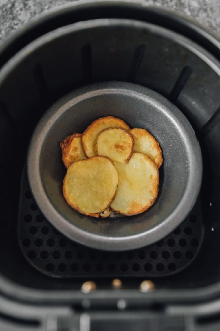 Egg mixture being poured over cooked potatoes and onions in air fryer tins, ready to cook.