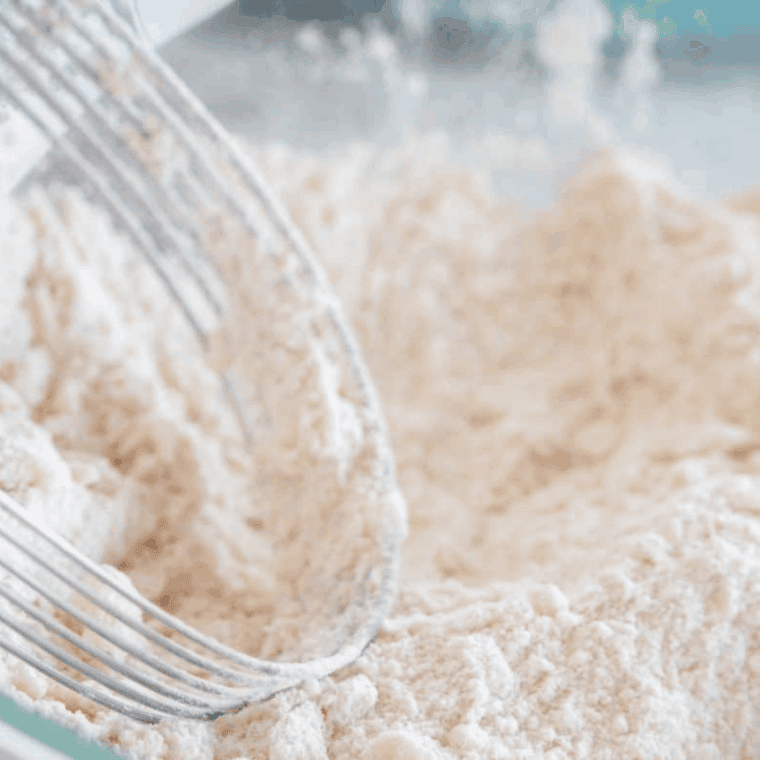 Large mixing bowl with flour, sugar, baking powder, cinnamon, and salt combined into a crumbly mixture.