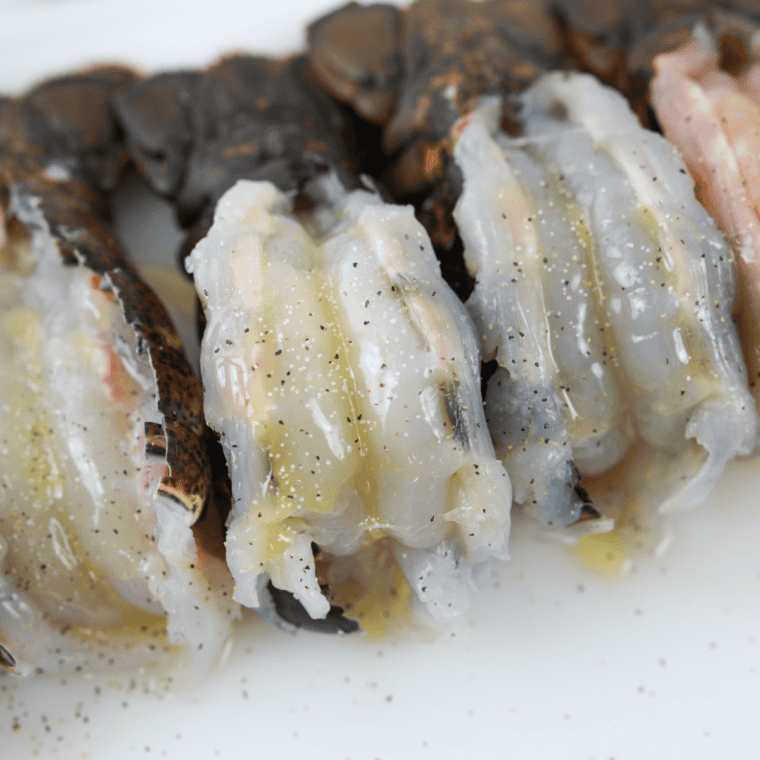 Lobster tails placed meat-side up on a wire rack over a Blackstone Griddle with water added for steaming under a melting dome.