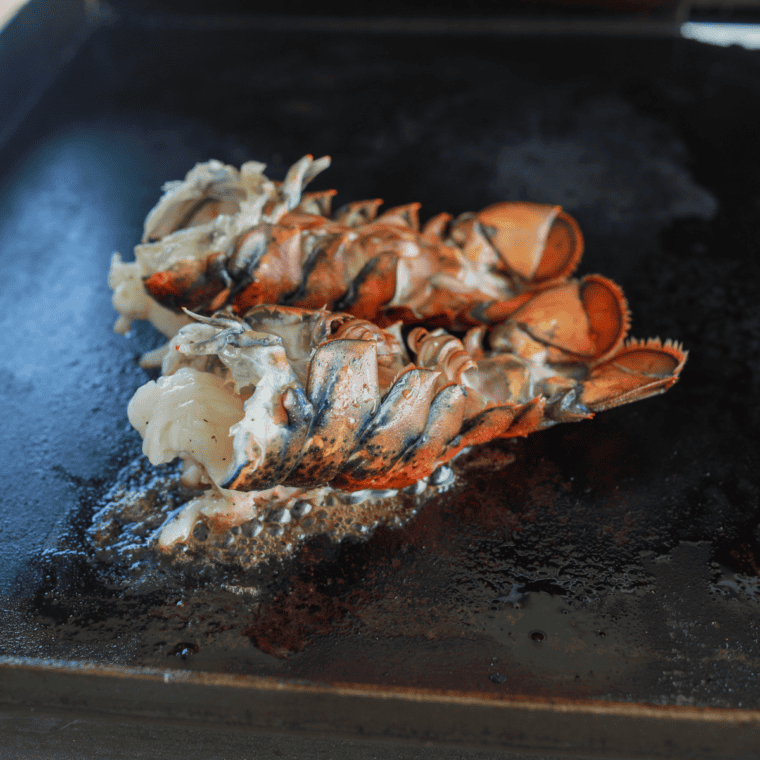 Fully cooked lobster tails removed from the Blackstone Griddle and served with melted butter and fresh lemon wedges.