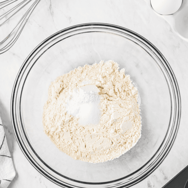 Powdered sugar being sifted into a medium glass bowl