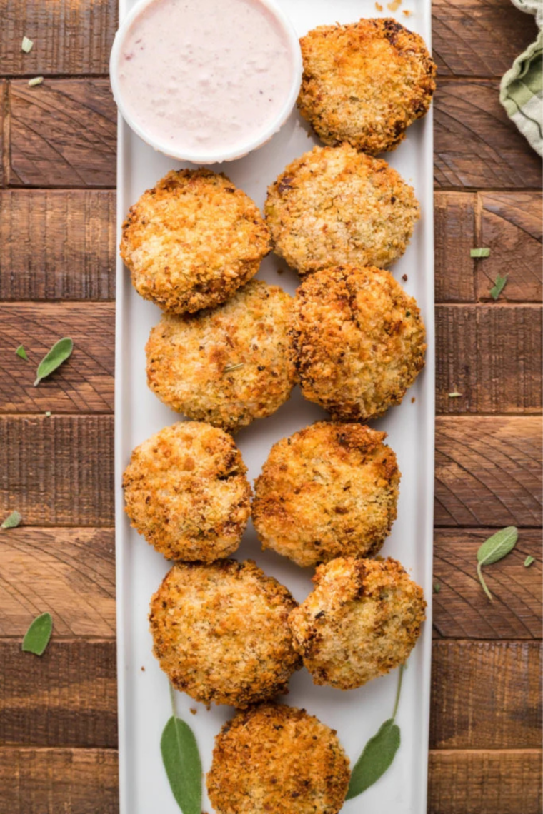 Plate of homemade fritters on a rustic table with a bowl of cranberry dip