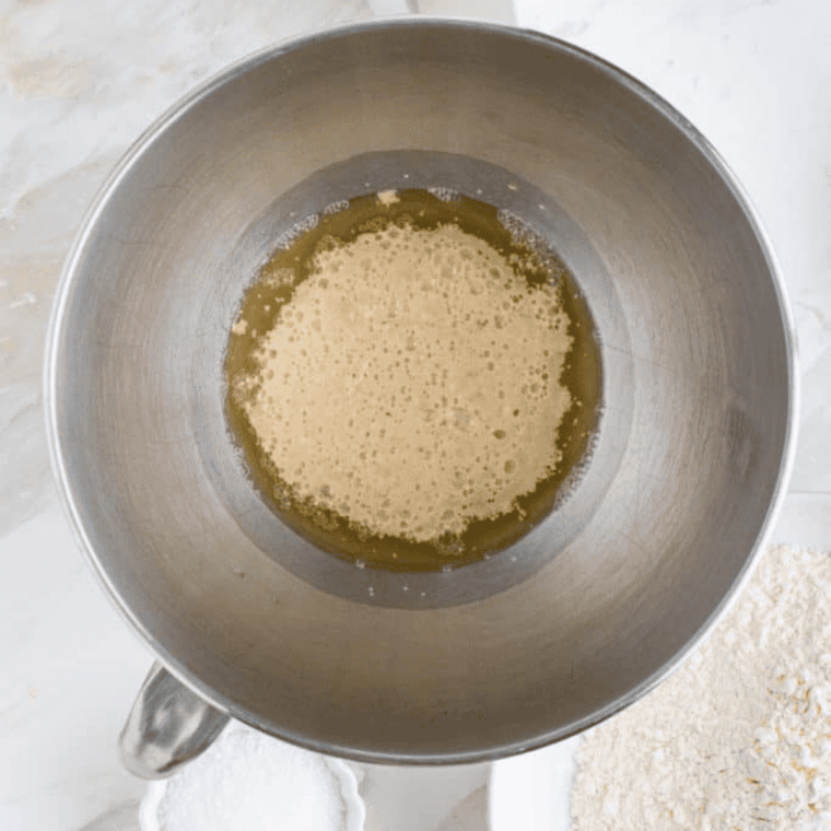 Yeast and brown sugar foaming in a bowl of warm water