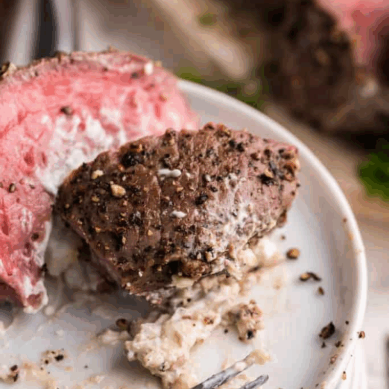 Sliced Black and Blue steak showing a dark, nearly black crust and a cool, bright red interior (blue-rare), served on a white plate.