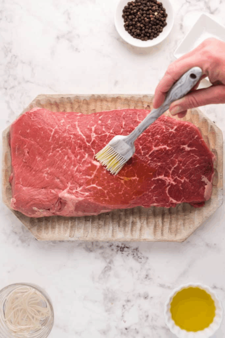 Raw steak rubbed with olive oil and heavily coated in a coarse salt and black pepper crust.