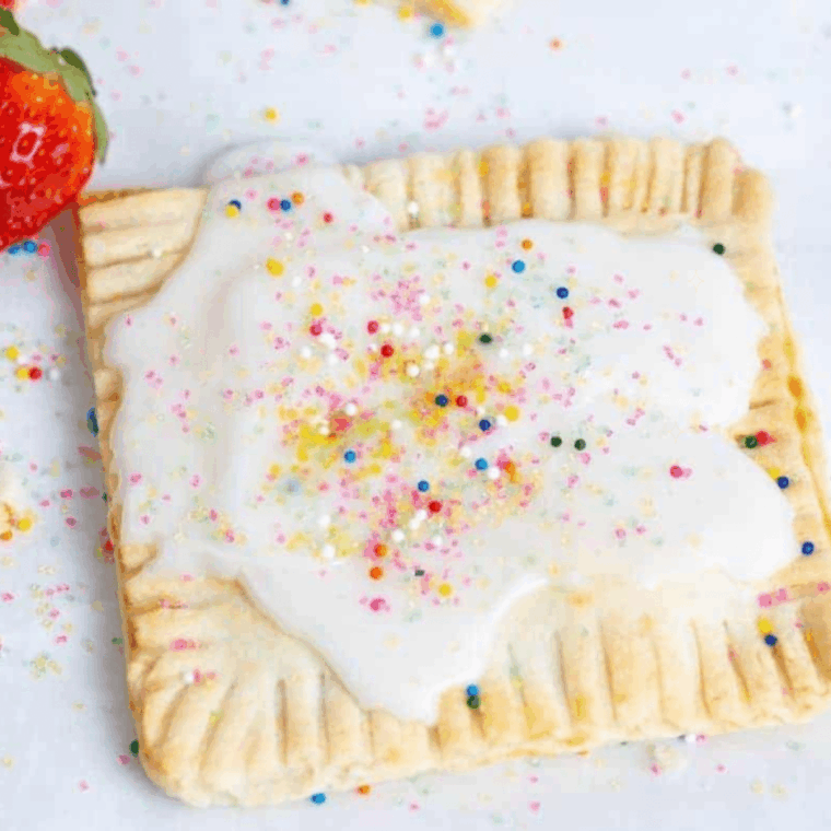 Golden air fryer strawberry pop-tarts with white icing and colorful sprinkles served on a plate.