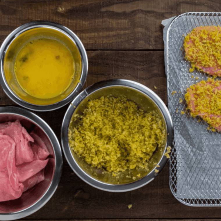 Preparing thin veal cutlets by patting them dry with a paper towel before breading.