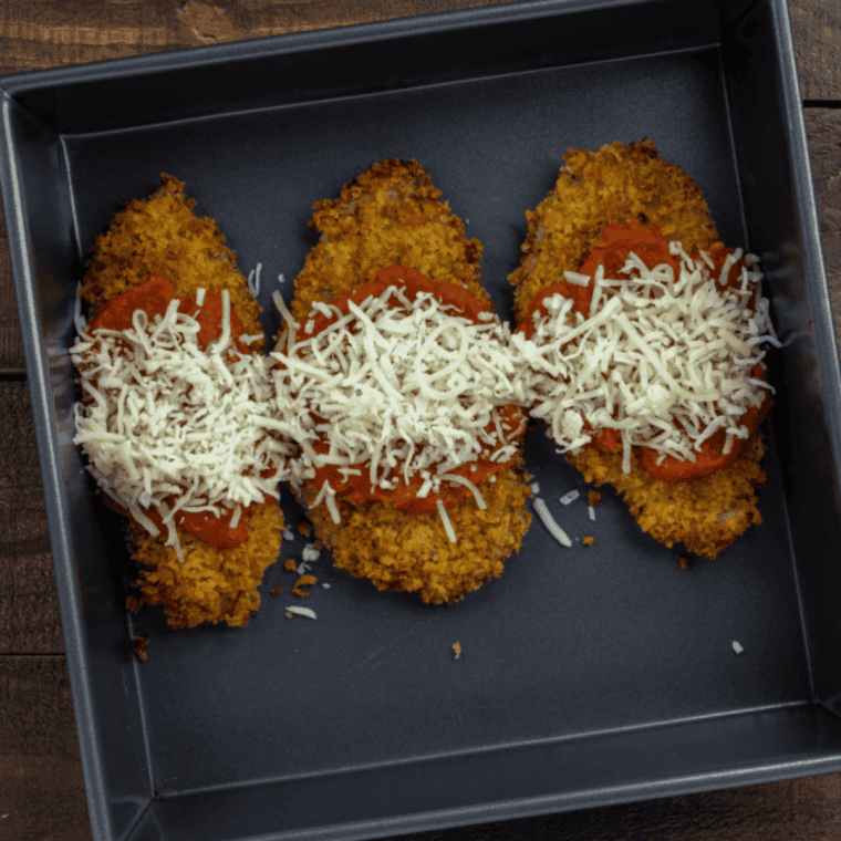 Air fryer veal Parmesan cooking, golden brown and crispy, served with lemon wedges and fresh parsley.