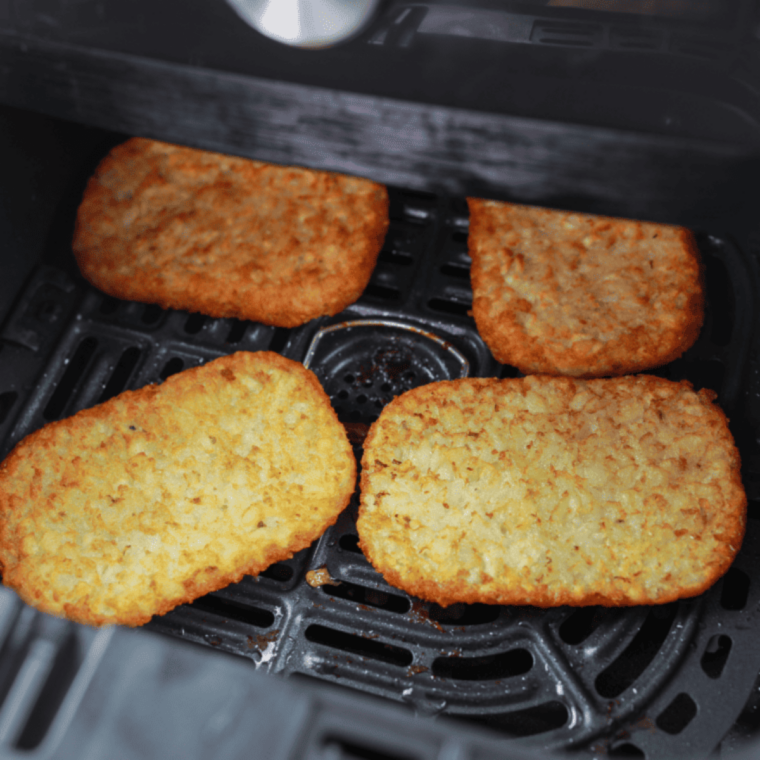Four crispy Trader Joe's hash browns cooked in air fryer on white plate