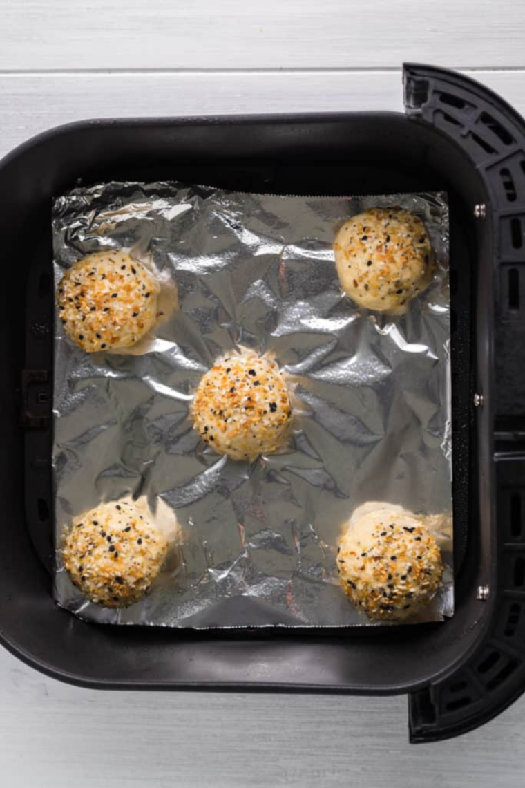 Placing the prepared bagel bites in the air fryer basket for cooking.