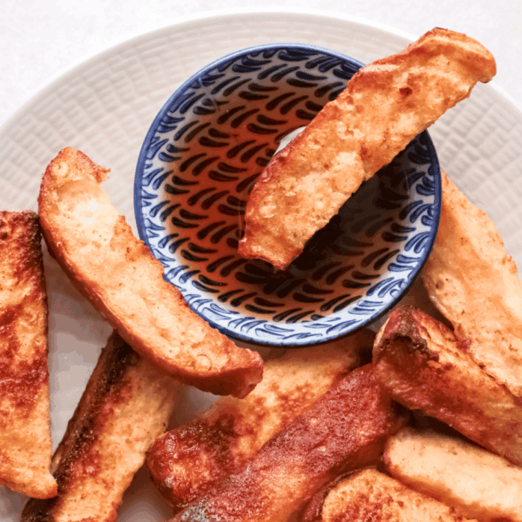 Golden brown air fryer French toast sticks with apple filling, dusted with cinnamon sugar, served on a plate.