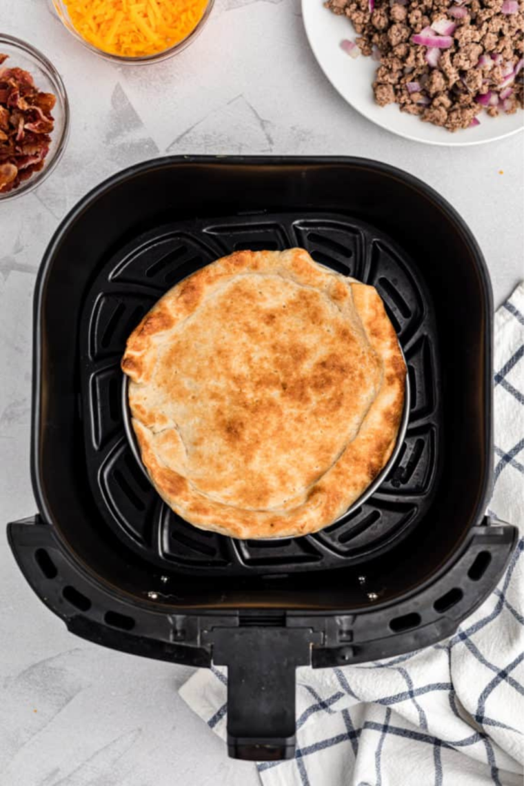 Golden par-baked pizza crust with a dry, lightly browned surface ready for toppings