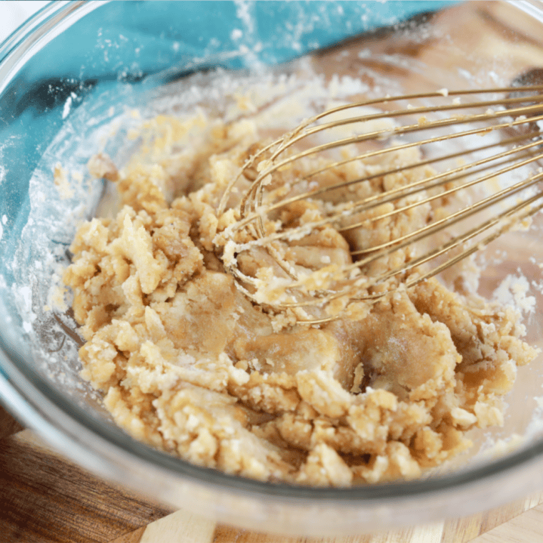 Mixing bowl with flour, sugars, butter, egg, and vanilla for cookie dough.