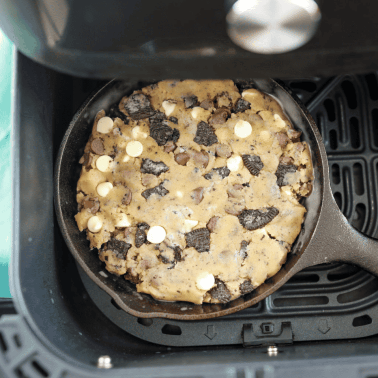 Cookie dough pressed into a greased pan with chocolate chips and crushed Oreos evenly mixed in.