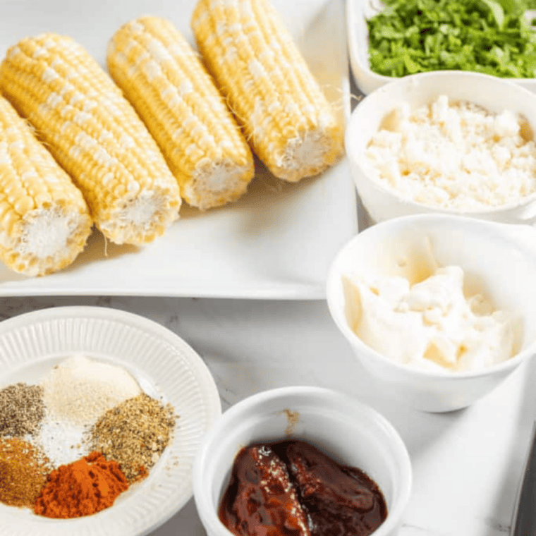 Ingredients for air fryer corn ribs: corn on the cob, mayonnaise, cotija cheese, chipotle peppers, lime, cilantro, and spices
